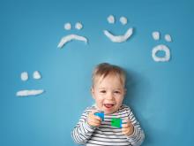 Little smiling boy on a blue background with different emotions in wool