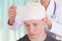 Doctor wrapping a young males head in bandages, mild brain trauma