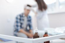 Selective focus of bottles with medicine, whilst a man has his head wrapped in the background