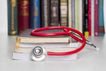 Red stethoscope on top of a pile of books