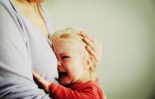 Distressed child crying in his mother's arms
