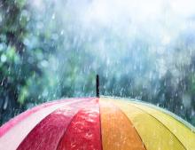 Rain belting down on a rainbow umbrella