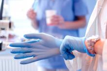 Female doctor's hands putting on blue sterilized surgical gloves in a medical clinic